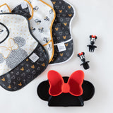 Bumkins Silicone Chewtensils®: Minnie Mouse lay next to 3 black & white bibs and a Minnie Mouse-shaped plate on a white background.