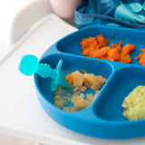 Close-up of a blue divided baby plate with carrots & puree on a highchair tray, paired with Bumkins Silicone Chewtensils®: Blue Jelly.