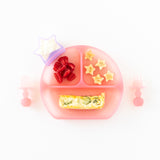 Bumkins Silicone Chewtensils®: Pink Jelly sit by a pink divided plate with quiche, fruit, and yogurt in a star cup on a white background.