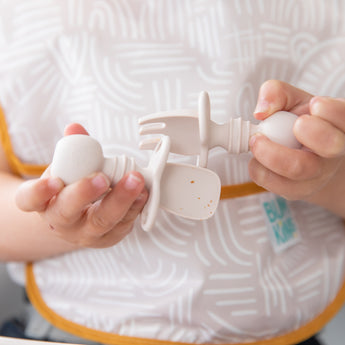 Close-up of a child exploring baby-led weaning with Bumkins Silicone Chewtensils®: Sand, featuring sensory bumps for an engaging mealtime.