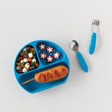 Blue tray with fruit salad, star snacks, corndog; Bumkins Spoon + Fork: Dark Blue for little hands beside it.