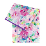 Bumkins Splat Mat: Watercolor showcases a stain-resistant, waterproof fabric with a floral design of pink, purple, green, and blue on white.