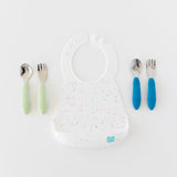 Bumkins Silicone Bib: Vanilla Sprinkle with green handle utensils on the left and blue handle utensils on the right on a white background.