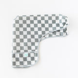 Bumkins Sleeved Bib: Charcoal Check lays folded lengthwise on a white background.