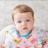 A blue-eyed baby wears a bib from Bumkins On-The-Go Mealtime 6-Piece Set: Boots + Pink.
