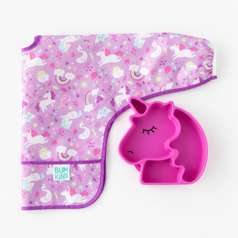 Bumkins Silicone Grip Dish Special Edition: Unicorn rests next to a folded unicorn patterned bib on a white background.