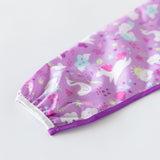 Close-up of Bumkins Sleeved Bib: Unicorns on a white background with focus on the elastic cuff on the sleeve.
