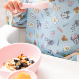 Close-up of a child eating breakfast with Bumkins On-The-Go Mealtime 5-Piece Set: Mickey + Minnie Mouse Sunny Side Up Pink.