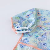 Close-up of Bumkins Sleeved Bib: Aloha Stitch on a white background, highlighting the white elastic cuff on the sleeve.