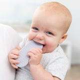 A smiling baby chews on a Bumkins Silicone Teether: Nintendo SNES™ Controller, enjoying soothing gum relief.