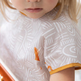 Close-up of a child wearing a Bumkins Junior Bib: Wander with a stain, highlighting the importance of its waterproof fabric.