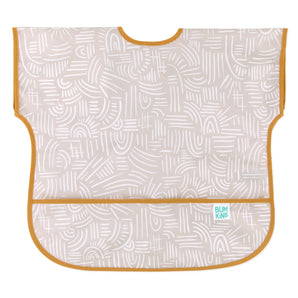 Bumkins Junior: Bib Wander features beige waterproof fabric with abstract white patterns, orange trim, and a catch-all pocket.