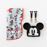 Bumkins Junior Bib: Mickey Mouse Classic lays folded next to a Mickey Mouse-shaped plate and matching utensils on a white background.