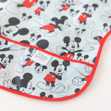 Close-up of Bumkins Junior Bib: Mickey Mouse Classic laid flat on a white background, with focus on the front pocket.