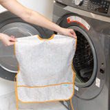 A person holds a Bumkins Short-Sleeved Smock: Wander in front of an open washing machine.