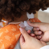 Hands secure the hook-and-loop closure of a Bumkins Short-Sleeved Smock: Grounded around a child's neck.
