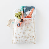 Bumkins Wet Bag: Palm Daze keeps sunglasses, toy palm tree, trunks, spade & towel dry with waterproof protection on a white background.
