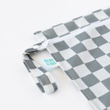 Close-up of Bumkins Wet Bag: Charcoal Check on a white background, with focus on the side handle, zipper, and logo tag.