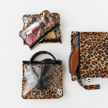 Roamio by Bumkins The Commuter Essential 4-Piece Set: Leopard holds shoes, makeup, and headphones on a white background.