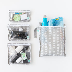 Bumkins The Chaos Coordinator Essential 4-Piece Set: Lunar Phase is neatly arranged on a white background, holding swim gear and toiletries.