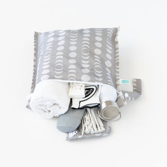 A bag from Bumkins The Playdate Planner Deluxe 5-Piece Set: Lunar Phase holds a towel, bottle, and golf gear on a white background.