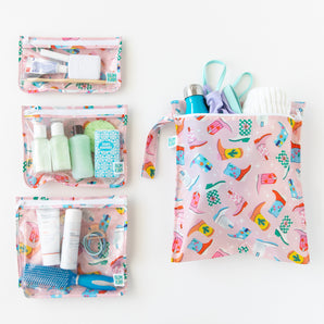 Bumkins The Chaos Coordinator Essential 4-Piece Set: Boots is neatly arranged on a white background, holding swim gear and toiletries.