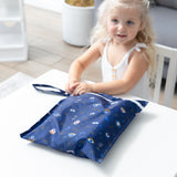 Smiling girl sits with Bumkins Wet Bag + Clear Travel Bag 3 Pack Set: Evil Eye—ideal for busy, on-the-go parents.