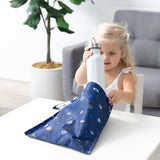 A child puts a bottle into Bumkins Wet Bag: Evil Eye at a white table.