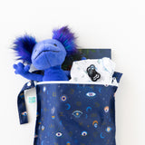 Bumkins Wet Bag: Evil Eye holds a blue plush toy, clothes, a book, and a pacifier on a white background.