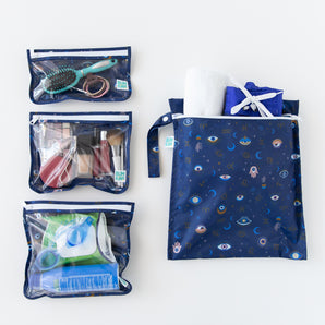 Bumkins The Chaos Coordinator Essential 4-Piece Set: Evil Eye is neatly arranged on a white background, holding makeup and swim gear.