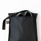 A bag from Bumkins The Chaos Coordinator Essential 4-Piece Set: Rich Black holds gray shoes on a white background.