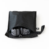 A Bumkins Wet Bag 2 Pack: Sand and Black Check holds gray shoes on a white background.