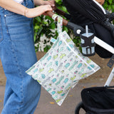 A person walks outdoors with a stroller and a Bumkins Wet Bag: Cacti hanging from the handle.