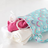 The Bumkins Wet Bag + Wet/Dry Bag Set in Rainbow holds pump parts, a pink diaper, and a white cloth on a white background.