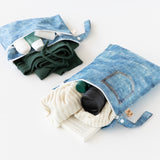 Roamio by Bumkins Wet Bag + Wet/Dry Clutch Set: Denim On Denim holds clothes and toiletries on a white background.