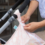 Close-up of hands unzipping a bag from Bumkins The Chaos Coordinator Essential 4-Piece Set: Lace attached to a stroller handle.
