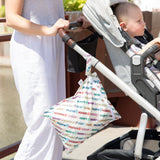 A person pushes a stroller with a toddler; a Bumkins Disney Mickey & Friends Wet Bag hangs from the handle.