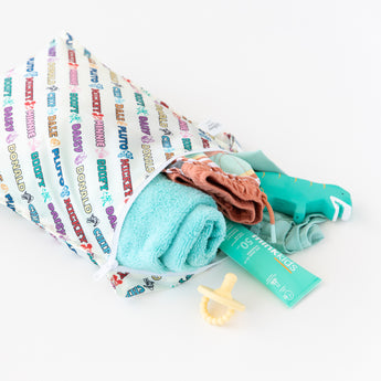 Bumkins Wet Bag: Mickey & Friends Varsity is shown on a white background holding a pacifier, folded towel, clothing, and sunscreen.