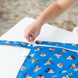 A child zips a Bumkins Wet Bag: Mickey & Friends Forever on a white table.
