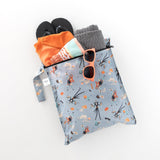 Bumkins Wet Bag: No Tricks, Just Treats holds orange swimwear, a towel, flip-flops, and orange sunglasses on a white background.