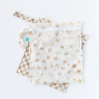 Bumkins Wet Bag 2 Pack: Palm Check, featuring two waterproof bags with palm tree and checkered patterns, lays overlapped on a white background.