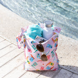 A Roamio by Bumkins Wet Bag 2 Pack: Disco Boots with summer essentials sits poolside on a sunny day.