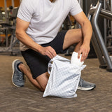 Man in gym gear puts a towel in a Roamio by Bumkins Wet Bag 2 Pack: Rich & Boujee, gym equipment in background.
