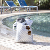 A Roamio by Bumkins Wet Bag 2 Pack: Rich & Boujee holds a towel, water bottle, camera & sunglasses by the pool.