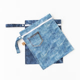 Roamio by Bumkins Wet Bag 2 Pack: Denim On Denim—two overlapping blue denim-patterned reusable, waterproof bags.