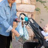 An adult hangs Bumkins Wet Bag 2 Pack: Disney Stitch Star-ring Up Trouble on a stroller handle as a baby looks up.