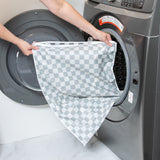 A person loading a Bumkins Extra Large Wet Bag: Charcoal Check into an open washing machine.