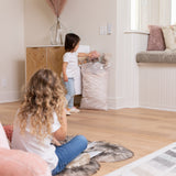 A child plays near a Bumkins Extra Large Wet Bag: Wander, filled with stuffed animals, while another child sits on the floor in a cozy room.