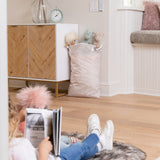 A child reads on a rug with a Bumkins Extra Large Wet Bag: Wander, filled with stuffed animals, at the other end of the room.