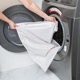 A person places Bumkins Extra Large Wet Bag: Wander into a front-loading washing machine.